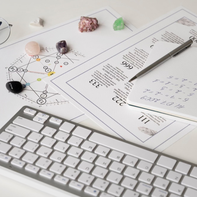 A keyboard, paper, and a pen arranged neatly on a desk, symbolizing preparation for a personalized numerology report.